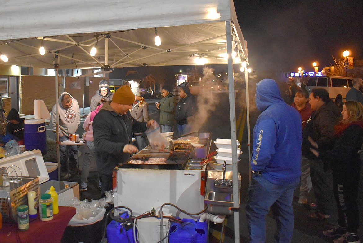 Mario Flores, owner of Porky’s Hot Dogs, serves up steaming hot sausages at the downtown tree lighting Friday.