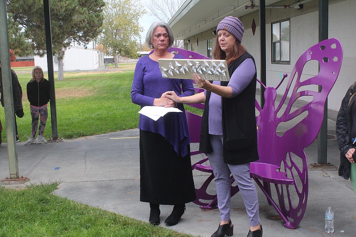 Lana Redal, left, fights back emotion as her friend and fellow Larson Elementary teacher Cara Galbraith reads the dedication on a plaque that will be added to a bench built in memory of Redal’s granddaughter Ella Muongmany on November 4, 2022. Muongmany was lost in a 2018 car accident and the pictured bench, honoring her spirit, is to help students at Larson Elementary connect with those that need friends.