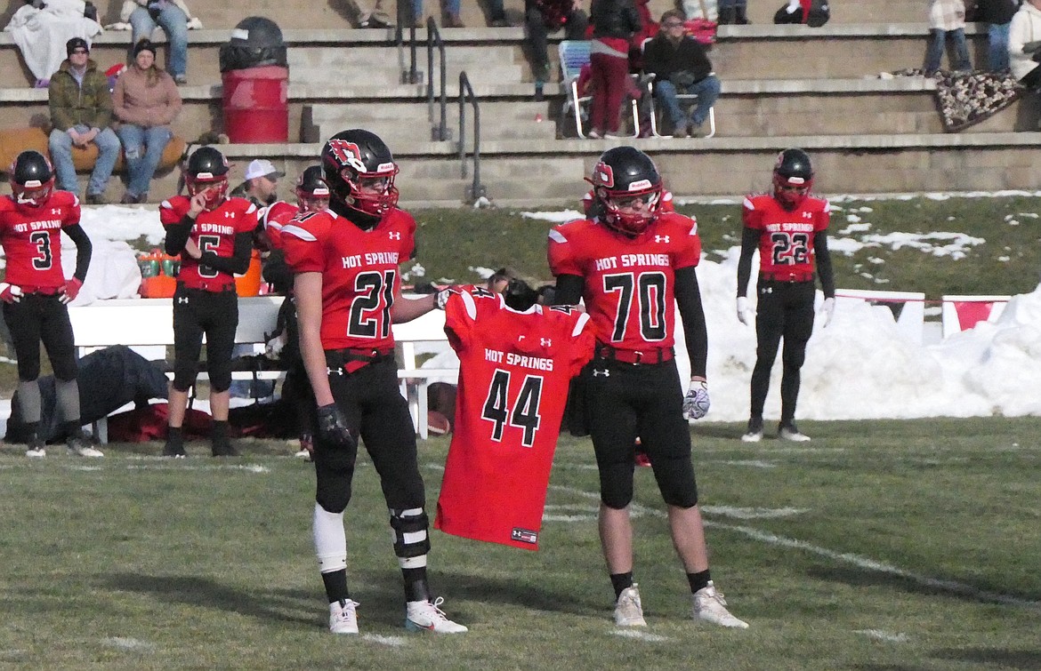 Hot Springs teammates Quincy Styles-Depoe (21) and Calvin Timmer (70) hold fallen teammate Jody Page's jersey during opening ceremonies of the Savage Heat's 40-6 playoff win over Valier two weeks ago.  (Chuck Bandel/VP-MI)