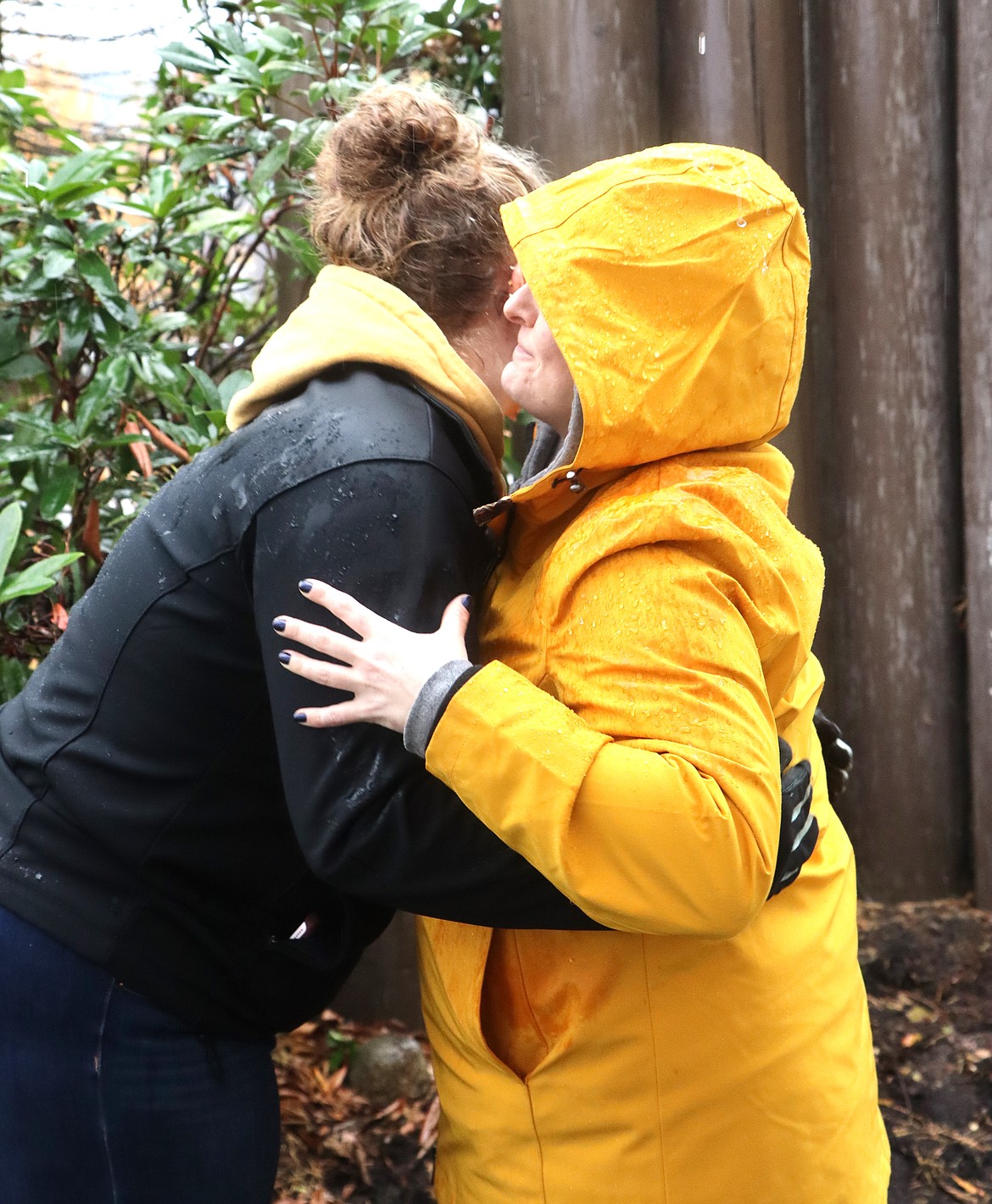 Melanie Fry, left, and Kate Colvin hug during a planting of tulip bulbs in a memorial garden at the Harbor Center sign on Hubbard Avenue on Monday.