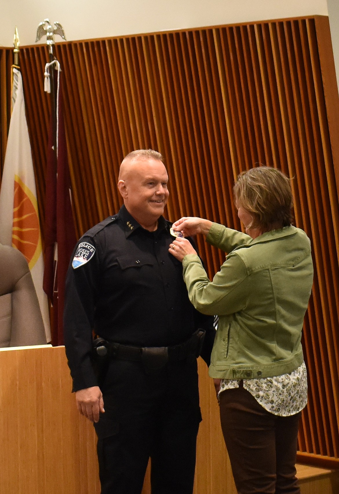 Kristin Sands, right, pins the chief’s badge on her husband, newly-sworn Moses Lake Police Chief Dave Sands at Tuesday’s Moses Lake City Council meeting.