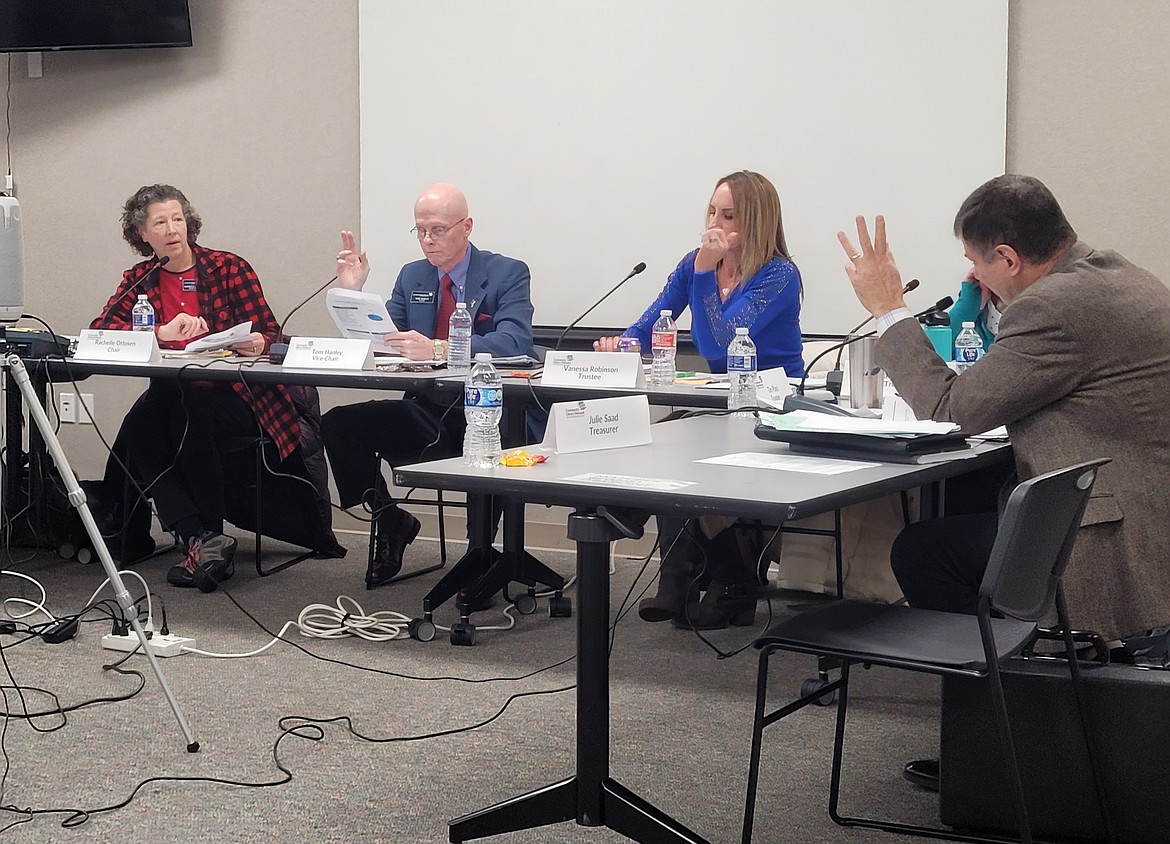 Trustees Tim Plass, right, and Tom Hanley raise their hands to speak at a meeting of the Community Library Network's board Thursday evening. From left: Rachelle Ottosen, Hanley, Trustee Vanessa Robinson and Plass.