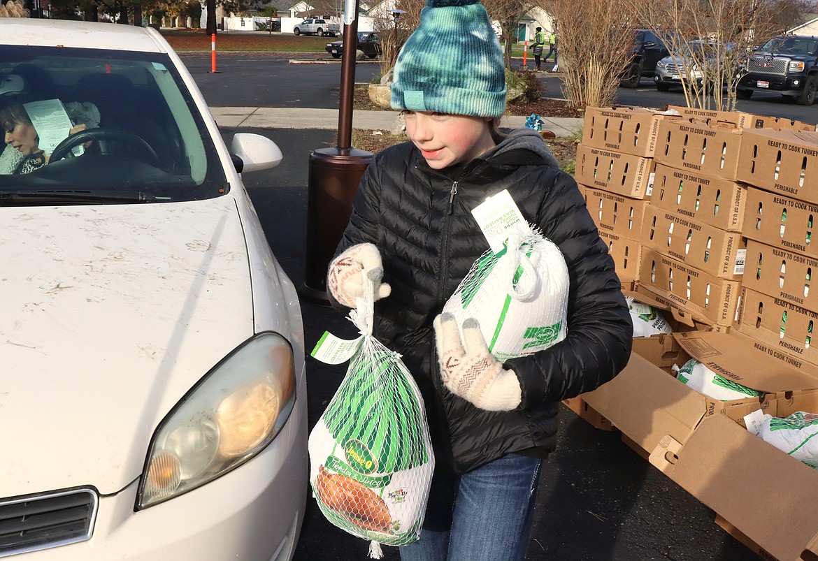 Keira Ellison carries a turkey to a car during the Turkeys and More distribution on Friday.