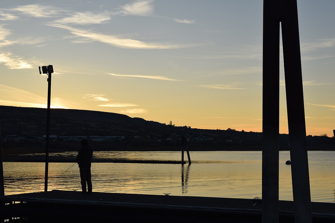 A fishing enthusiast enjoys a beautiful view of Potholes Reservoir from the docks at MarDon Resort Thursday evening. While the cold weather has changed fishing strategies a bit, fish are still biting if the right bait is used at the right depth.