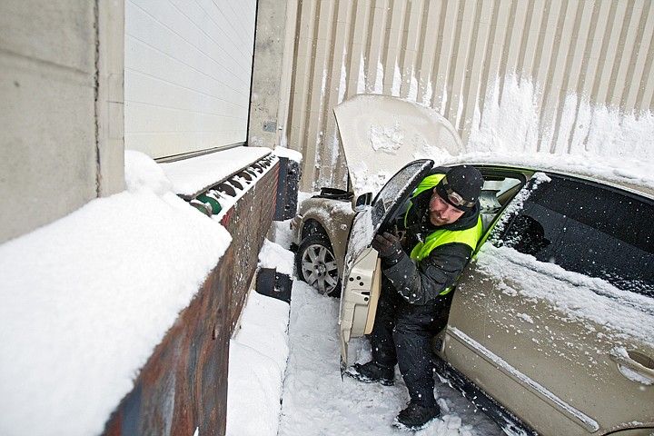 Derek Miller, with Schaffer's Towing, exits a vehicle after preparing it for towing in January of 2012 at the Coeur d'Alene Press loading dock where it crashed into the building. The driver, who was driving without a license, lost control of the vehicle in the snow on Second Street after turning off of Coeur d'Alene Avenue. There were no injuries reported.