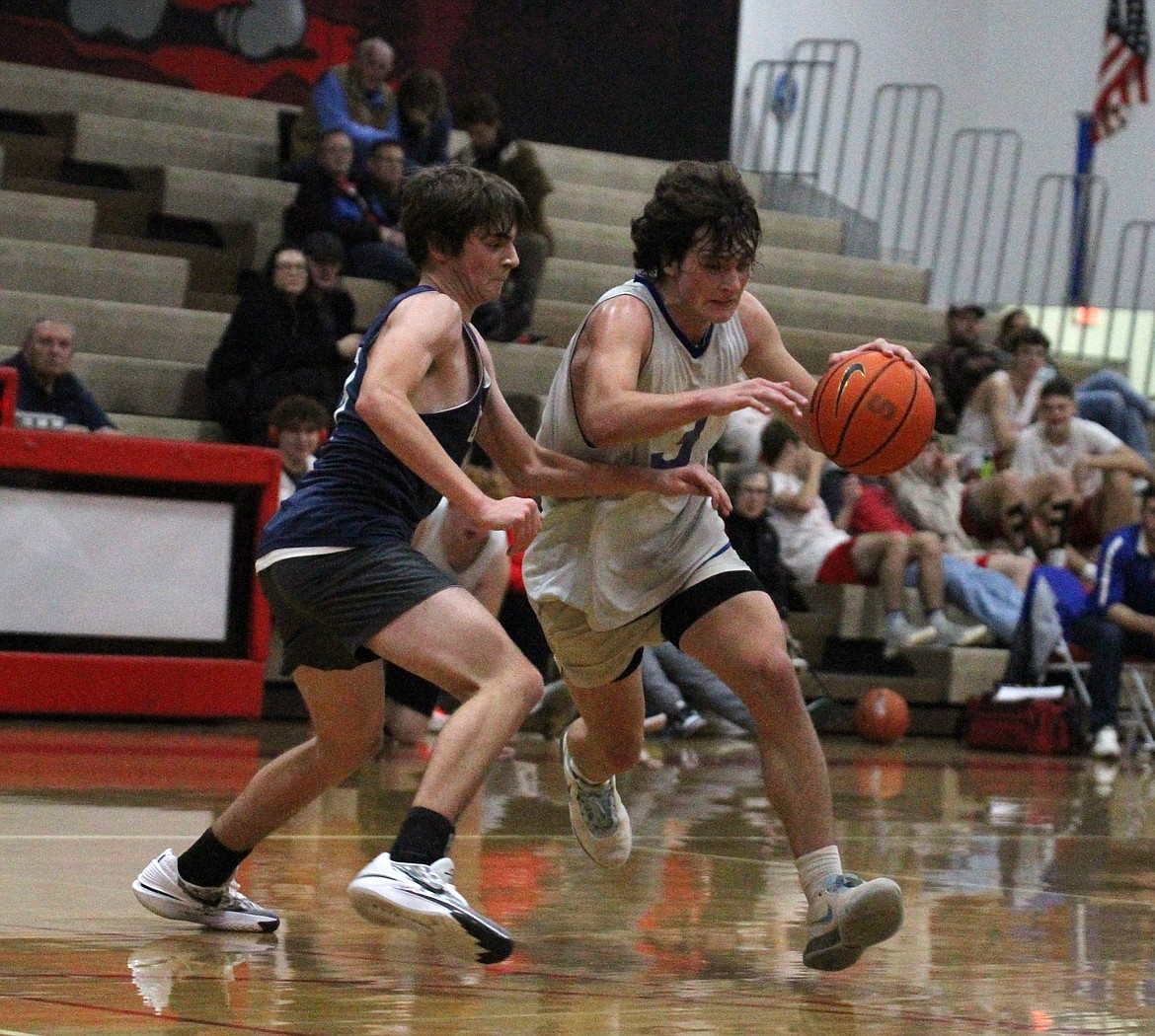 Clark Fork's Evrett Montgomery dribbles towards the basket while closely guarded by Bonners Ferry's Wyatt Smith.