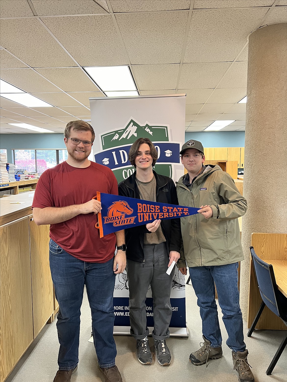 Riley Myers, Noah Darrin, and Matthew Norton display hold a banner showing their pride in Boise State University where the trio plan to attend college.