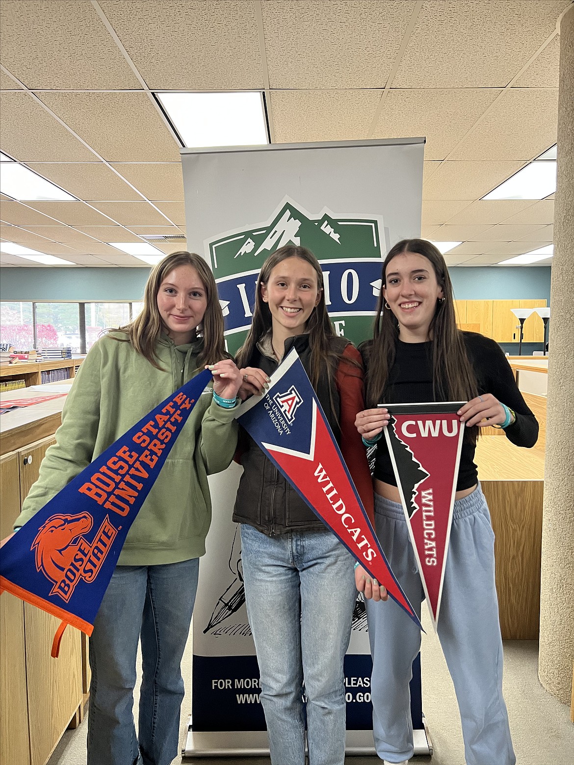 Saige Smith, Emele Dillon, and Aubree Lane display banners for the colleges they plan to attend during the school's recent Application Week event.