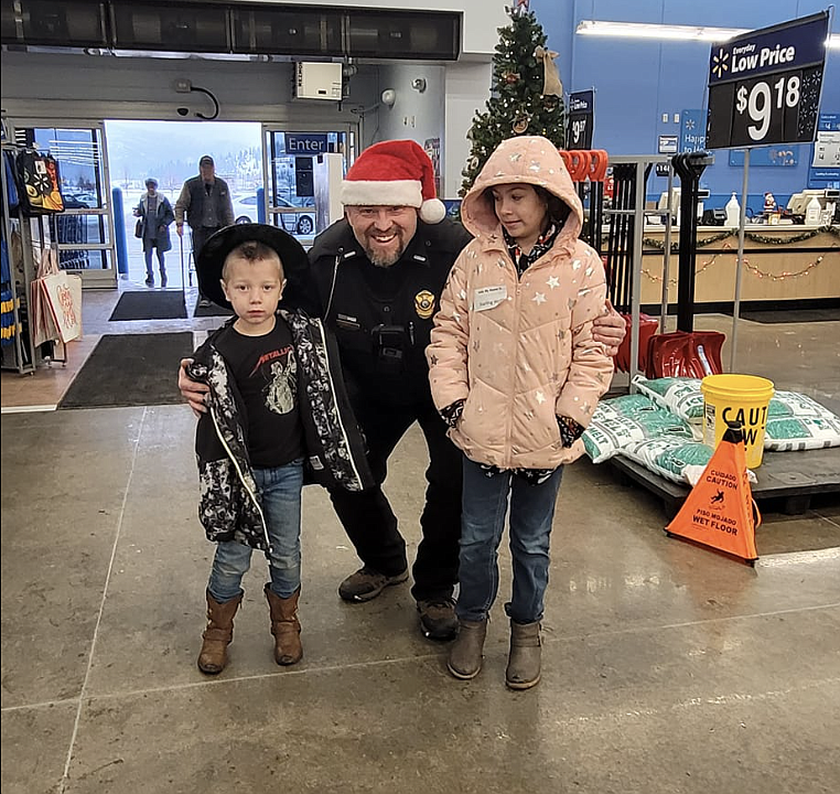 Jason Woody of Osburn Police smiles for the camera with his shoppers during the 2022 Shop with a Cop event.