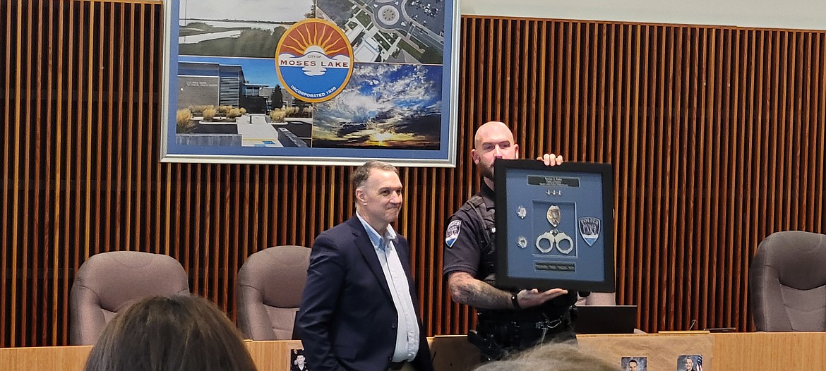 A Moses Lake police officer presents a retirement plaque from the Moses Lake Police Officers Association to former police chief Kevin Fuhr Tuesday afternoon.