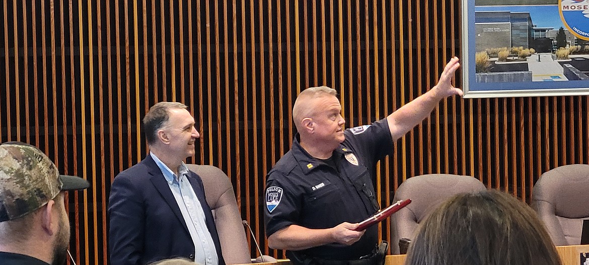 Newly appointed Moses Lake Police Chief Dave Sands, right, explains his vision for how the plaque celebrating his retirement from the Moses Lake Police Department, which Sands is holding, should be hung so as to be the star on one of the walls in City Manager Kevin Fuhr’s new office at city hall.