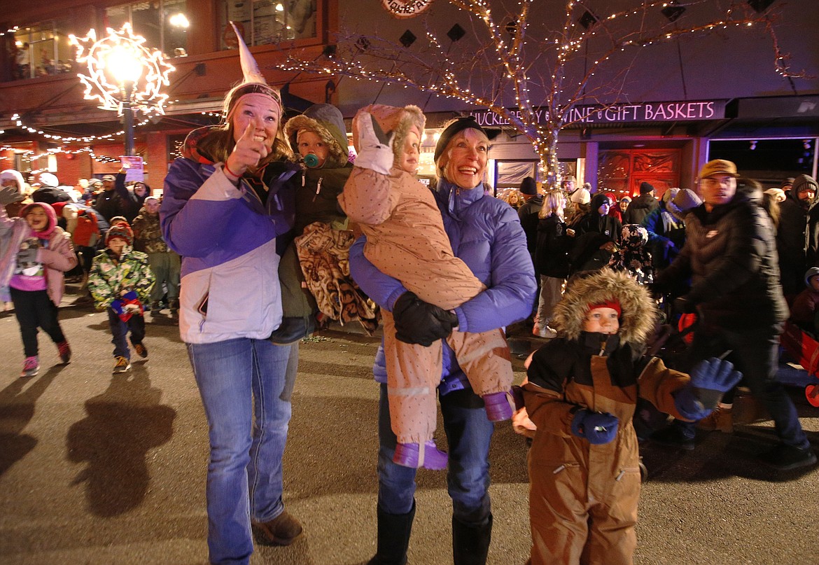 Amy Hofer, holding son Colton, and Diane Lawson holding Keeley Hofer, and Easton Hofer wave to Santa Claus in the Lighting Ceremony Parade on Friday in Coeur d'Alene.