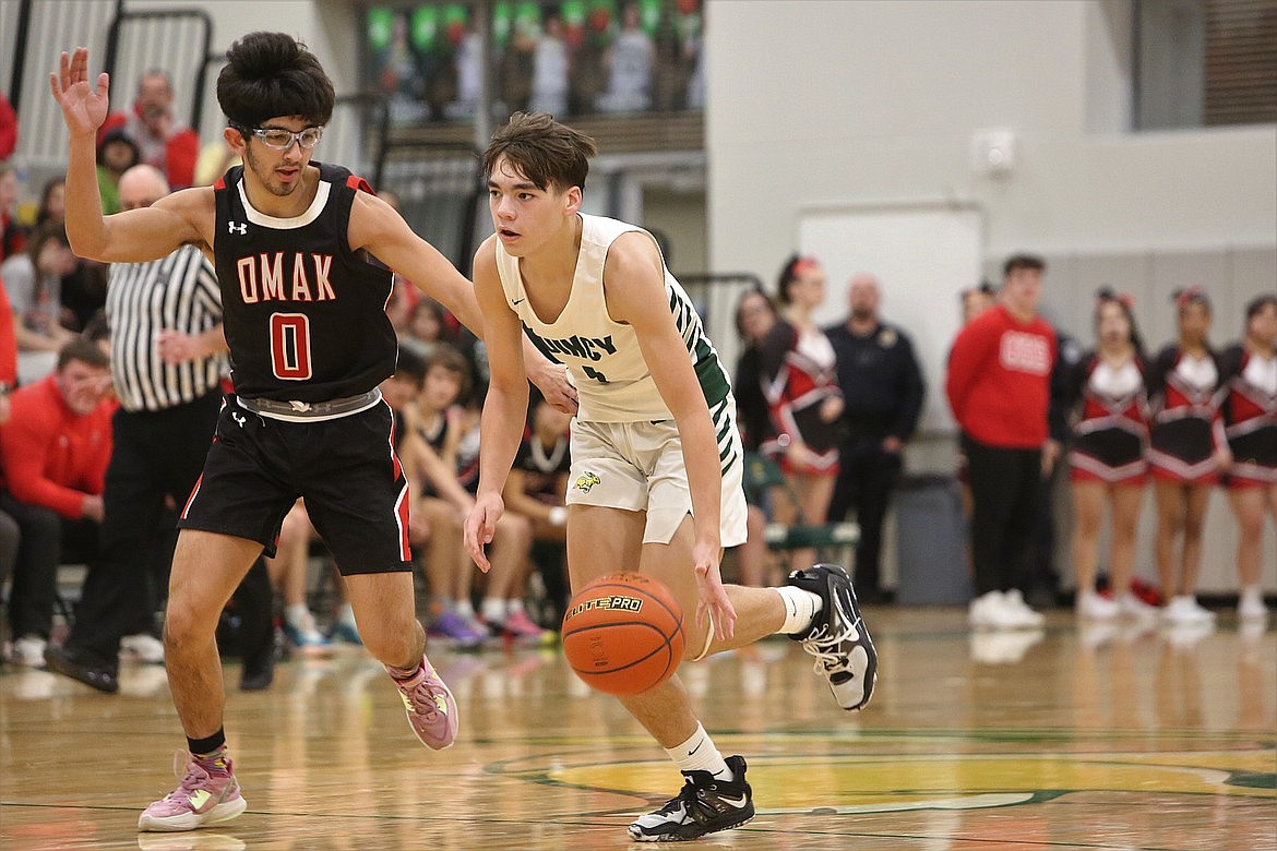 Quincy sophomore Pierce Bierlink, in white, brings the ball up the floor against Omak last season.