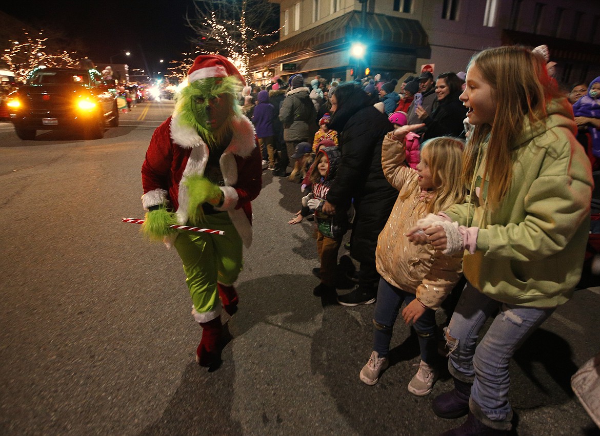 The Grinch creeps along the parade route as the crowd makes way.