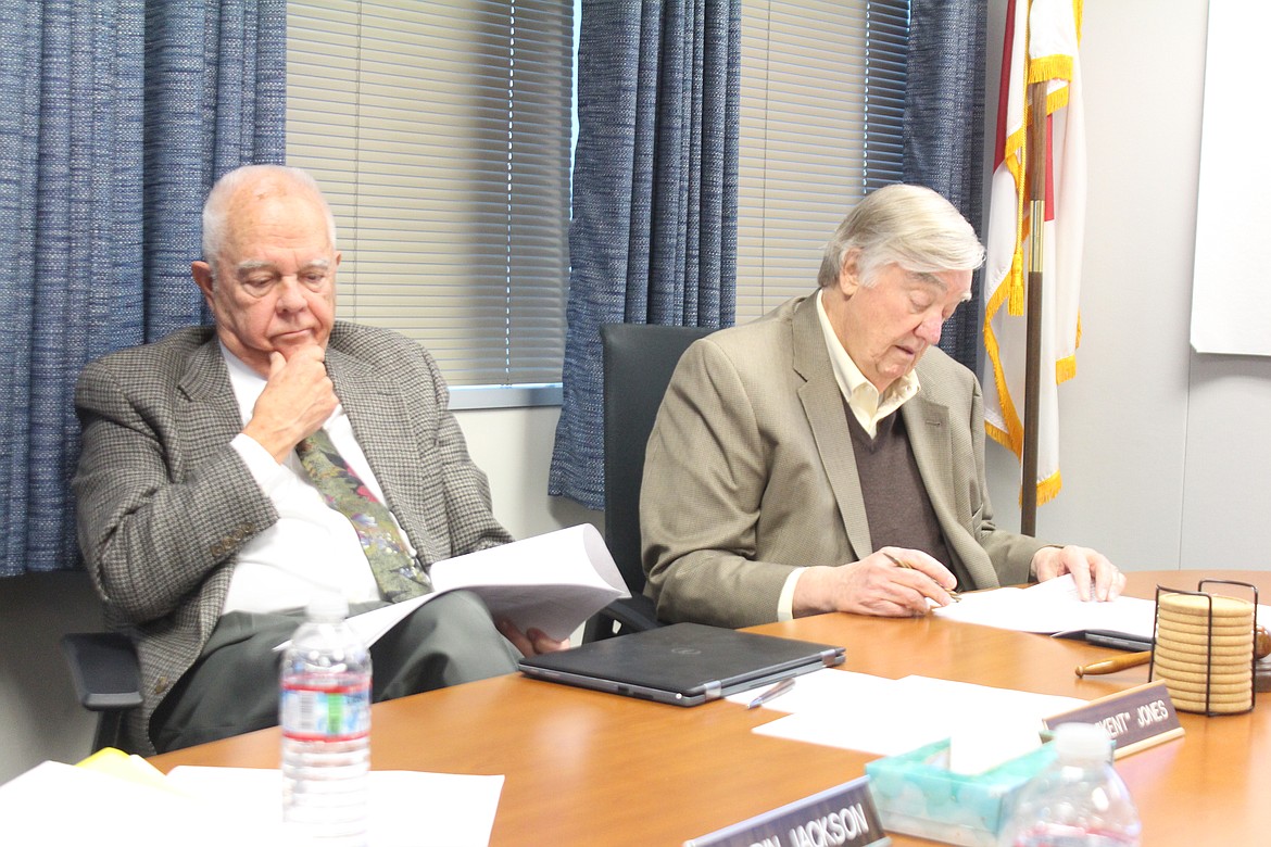 Port of Moses Lake commissioners Kent Jones, left, and Stroud Kunkle, right, study information from the city of Moses Lake during a discussion about the port taking ownership of the Moses Lake Municipal Airport.