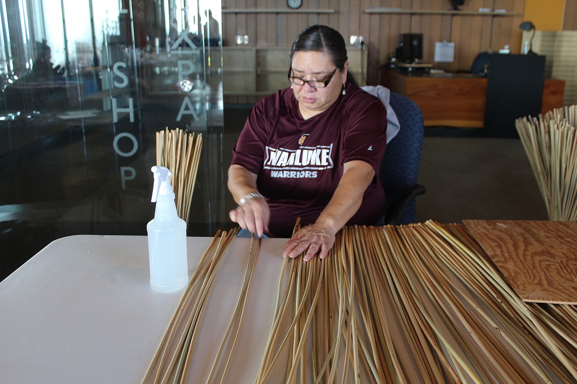 Emilee Maurice lays out the tule reeds that will be a table mat at the bazaar at the Wanapum Heritage Center Saturday.