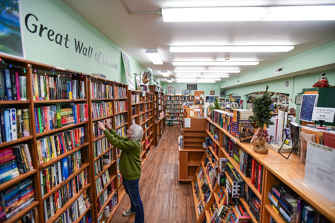Owner Cheryl Watkins organizes books in the Great Wall of Fiction section at Bookworks of Whitefish on Wednesday, Nov. 29. (Casey Kreider/Daily Inter Lake)