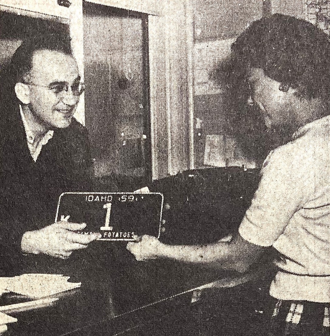 Charles Lunceford receives his No. 1 car license plate from Jeanne McArthur of the county assessor’s license bureau.