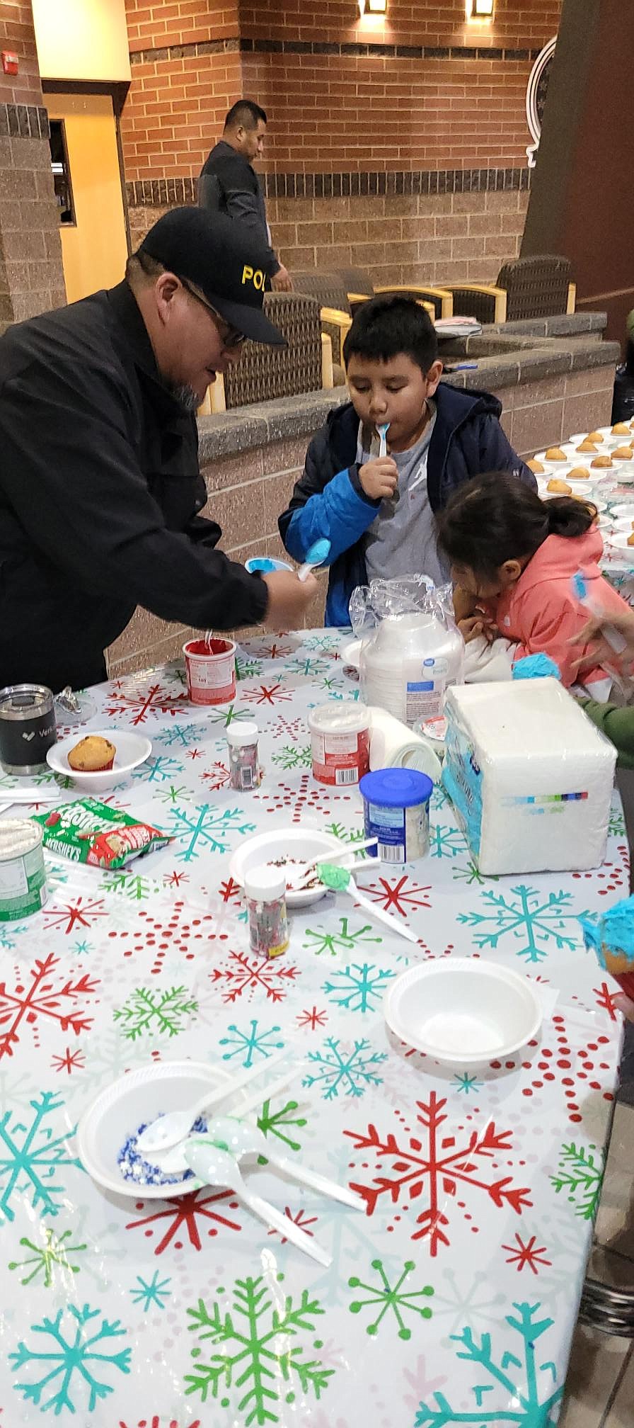 Mattawa Police Chief Robert Salinas helps a cookie decorator.