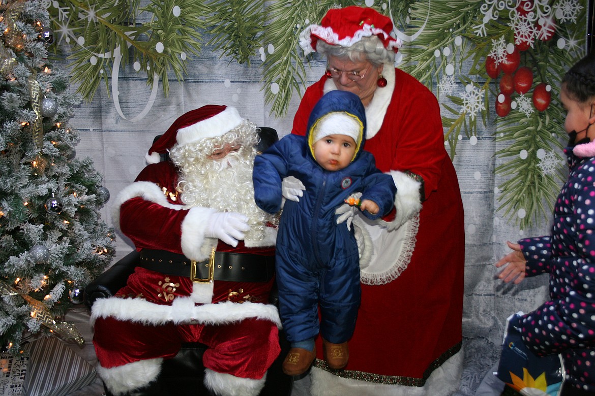 Santa and Mrs. Claus get ready for a picture with a well-bundled baby at the 2021 Christmas celebration in Mattawa.