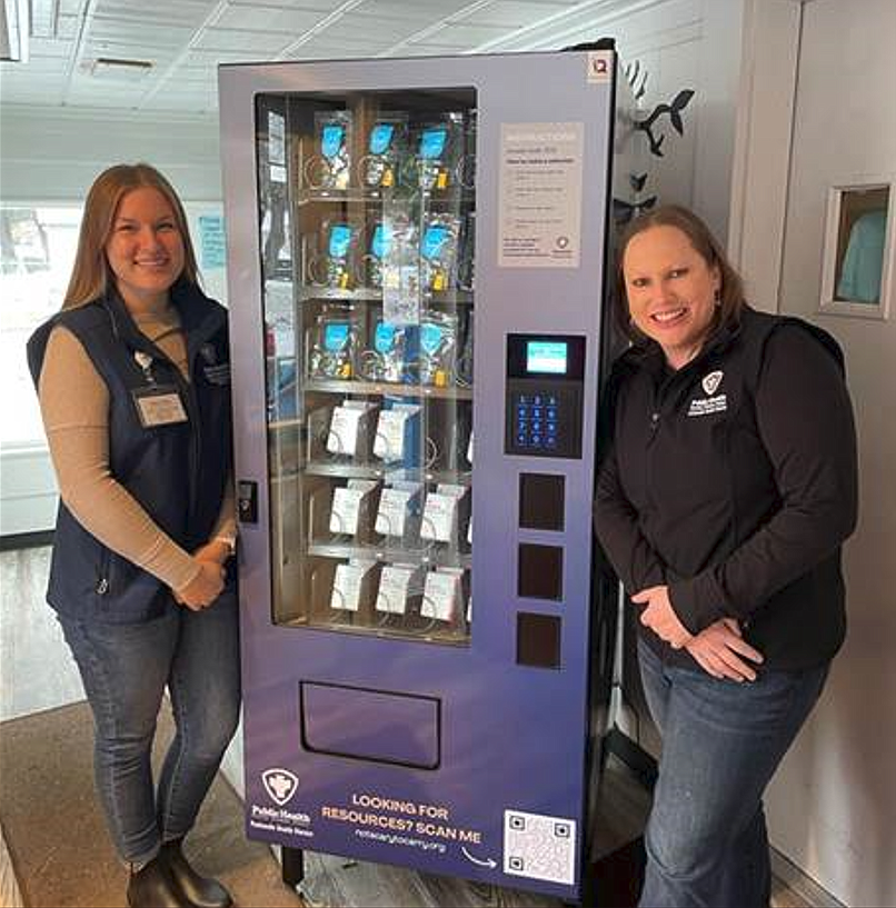 Panhandle Health staff members Katie Schmeer and Makenna Hunziker stand by the newly installed naloxone vending machine at St. Vincent de Paul in Coeur d'Alene.