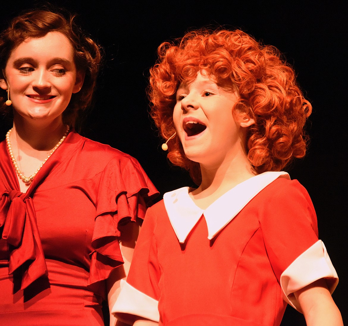 Annie, played by Katherine Bartel, sings her heart out as Grace Farrell, played by Dixie Montgomery, looks on approvingly. The two are appearing in the musical "Annie Jr." playing this weekend at Polson High School. (Berl Tiskus/Leader)