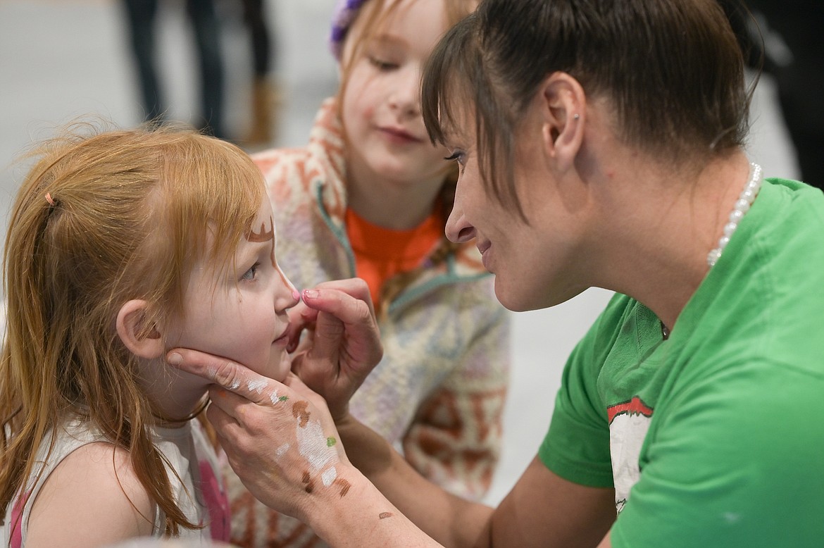 Expert face painter Randi Gariepy puts finishing touches on a young customer during the Christmas Carnival held Saturday in the St. Ignatius High School gym. (Christa Umphrey photo)