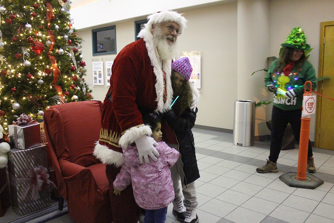 Santa (Kent Bacon), center, gets a hug from some fans at the Quincy Valley Christmas party Friday.