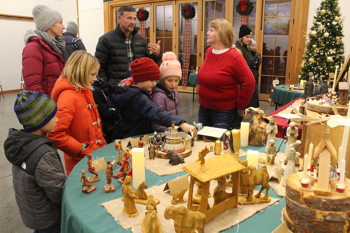 Children look over the Nativity scenes from the collection of Heidi Manly, right in red sweater, on display at the Quincy Valley Historical Society Friday.