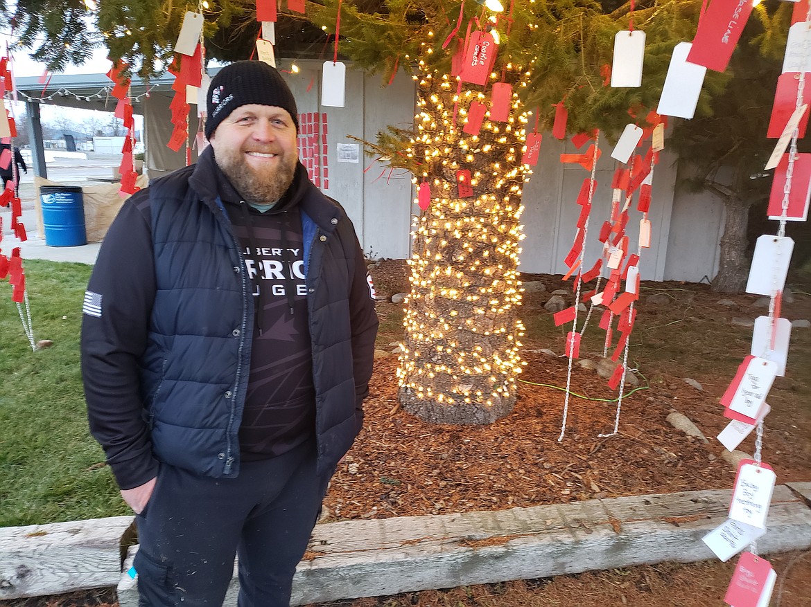Findlay Stadium Stateline Speedway owner Luke Kjar stands under the boughs of a giving tree. The community can take tags from the tree to buy gifts for families in need, referred by Newby-Ginnings.