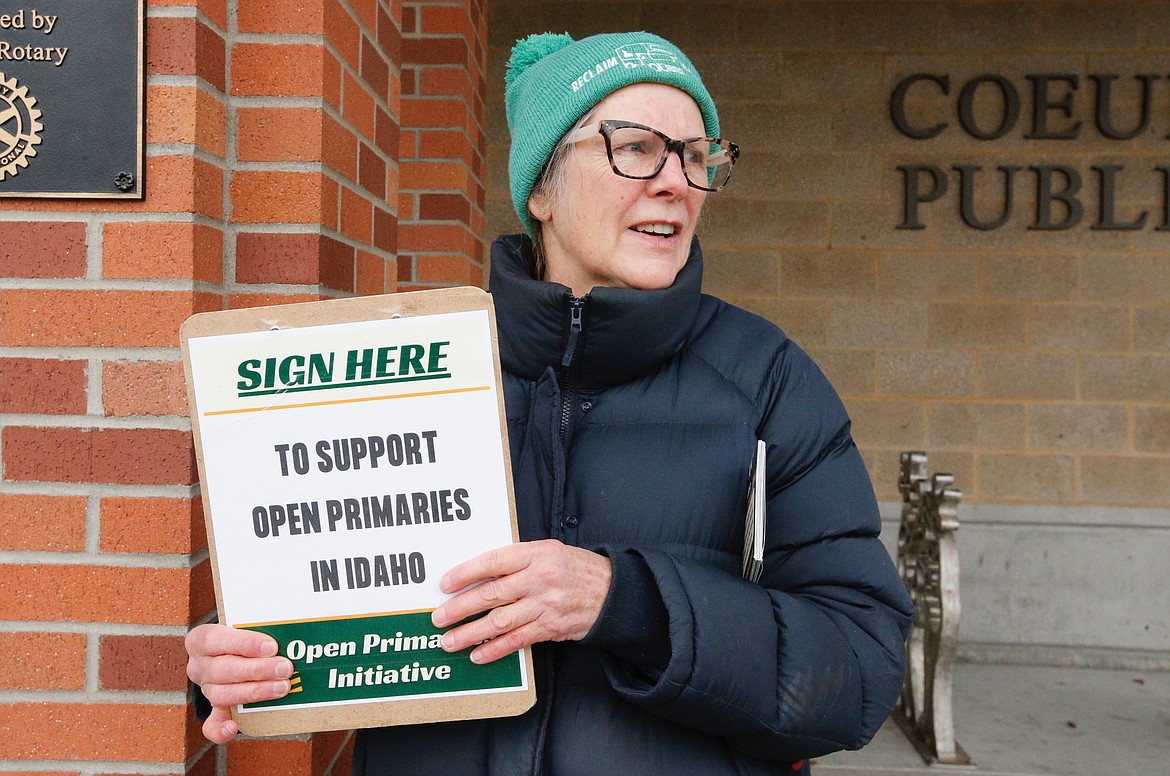 Spirit Lake resident Loree Peery catches the eye of a Kootenai County voter Saturday at the Coeur d’Alene Library. Peery is among a group of volunteers gathering signatures for an initiative to open Idaho’s primary elections to all voters.