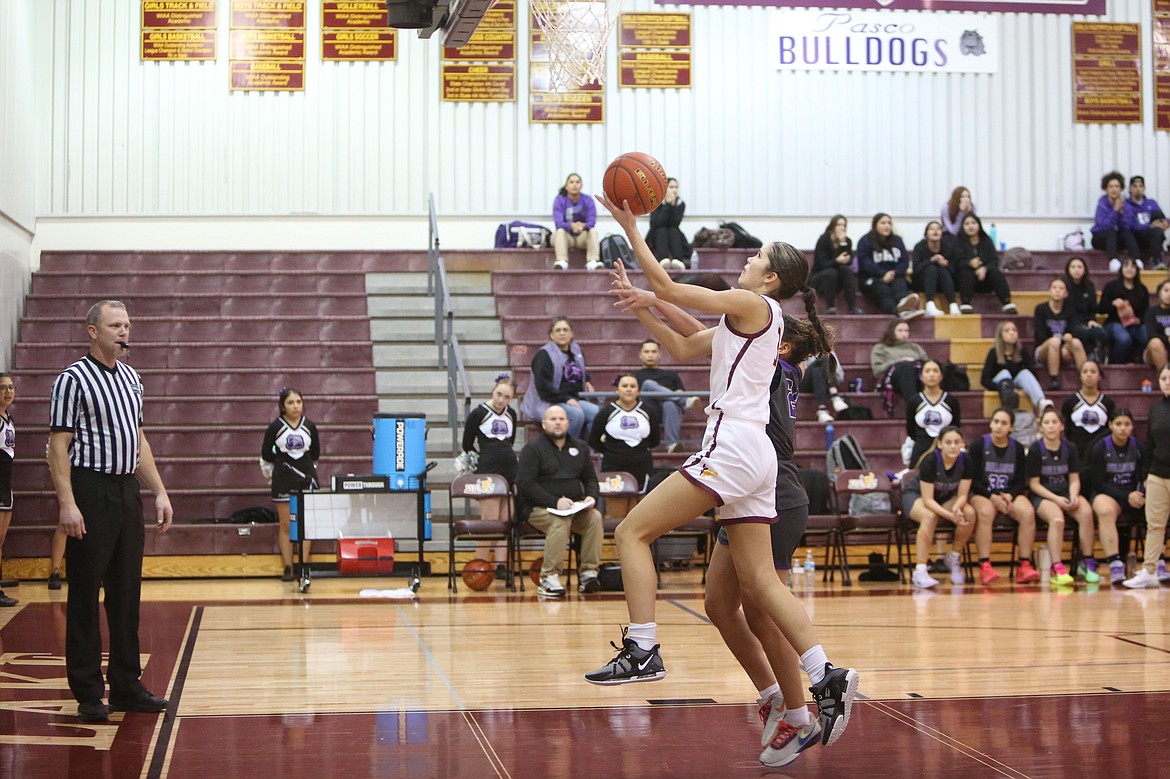 Moses Lake freshman Graycie Kast, in white, drives toward the rim in the first half against Pasco.