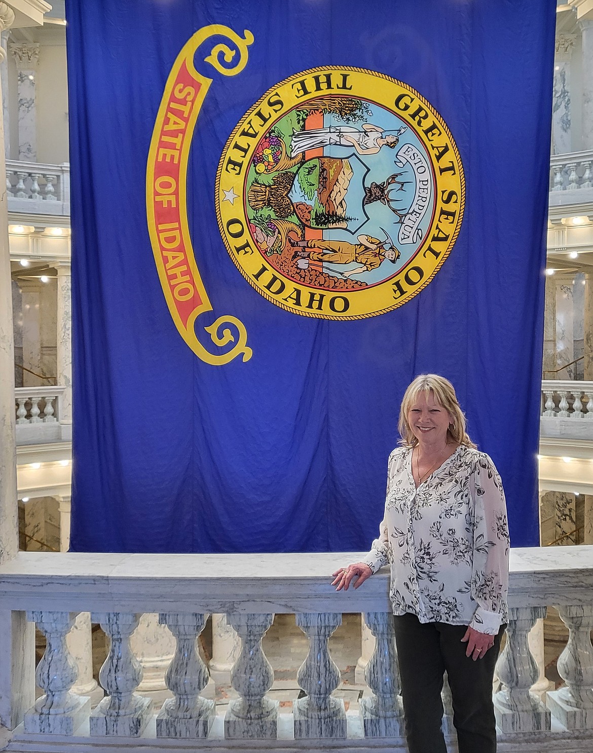 Tamie Lewis-Eberhard poses with the state flag in the Idaho State Capitol