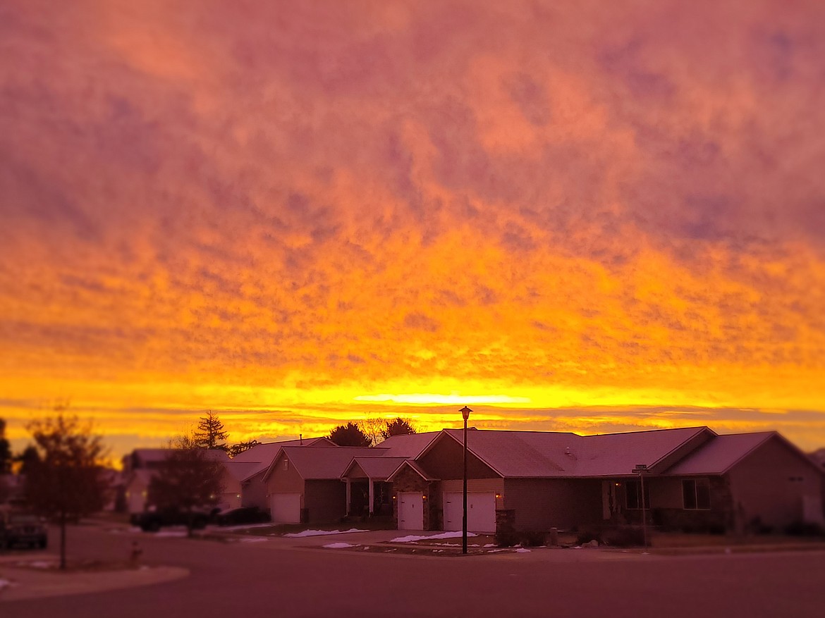 Sunlight paints the clouds a fiery orange Thursday morning over Post Falls as seen from just south of Poleline Avenue near Syringa Street.