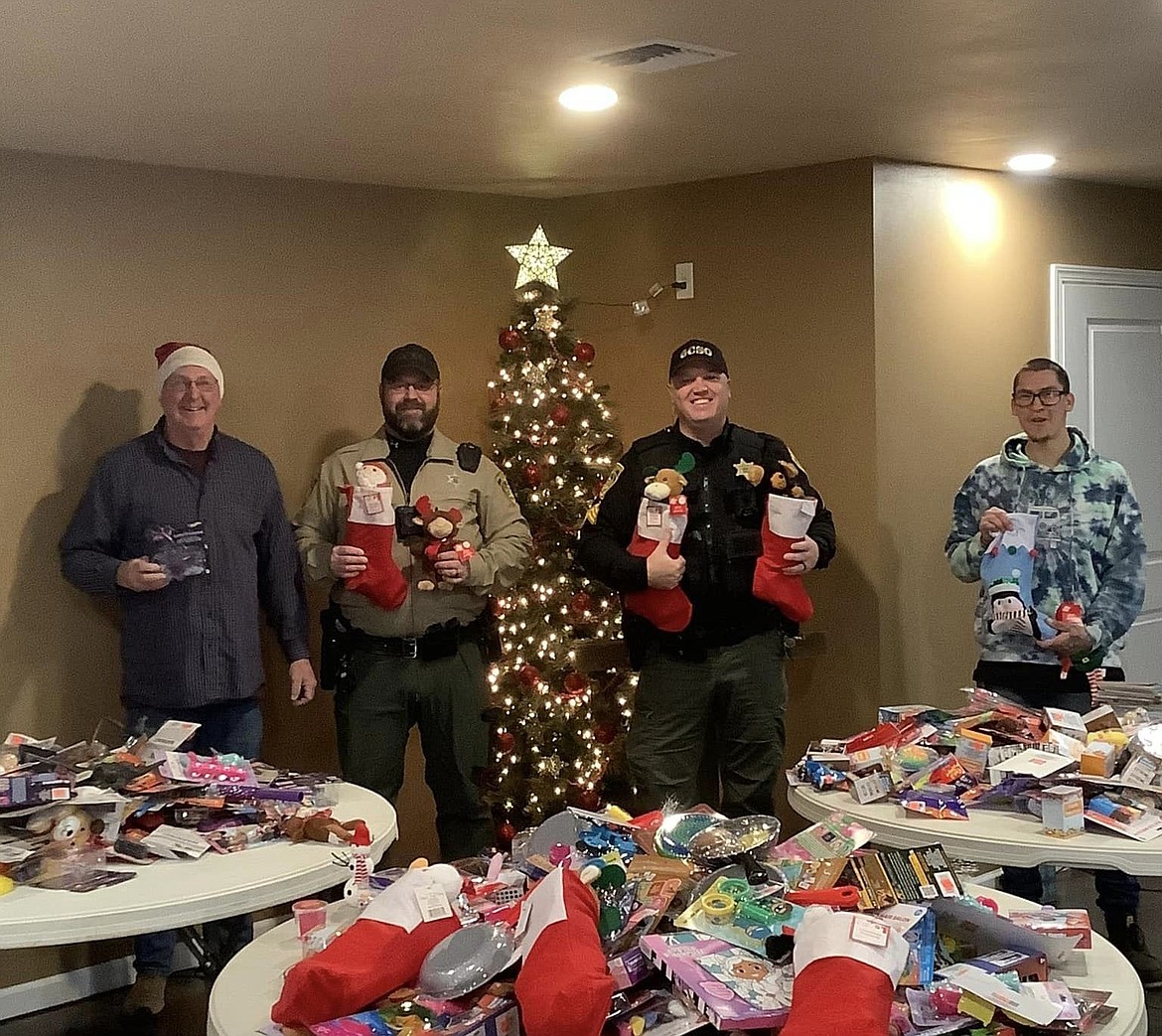 Grant County Sheriff's Office Deputy Tyson Voss and Sgt. Kyle Cox, right - in uniform, help the Light of Larson Church stuff Christmas stockings earlier this week.