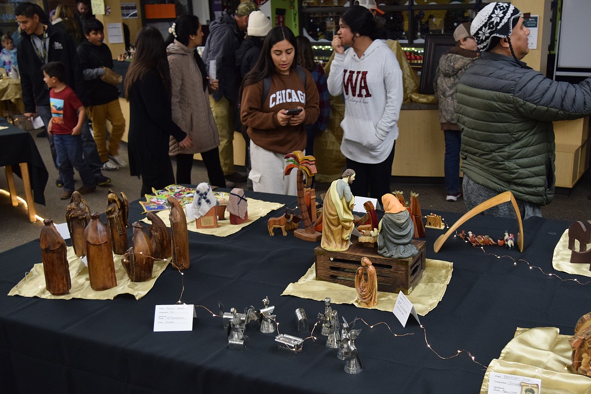 Several nativity displays sit on a table in the Wahluke High School library as community members walk through the tables of exhibits during the Living Nativity Project event.