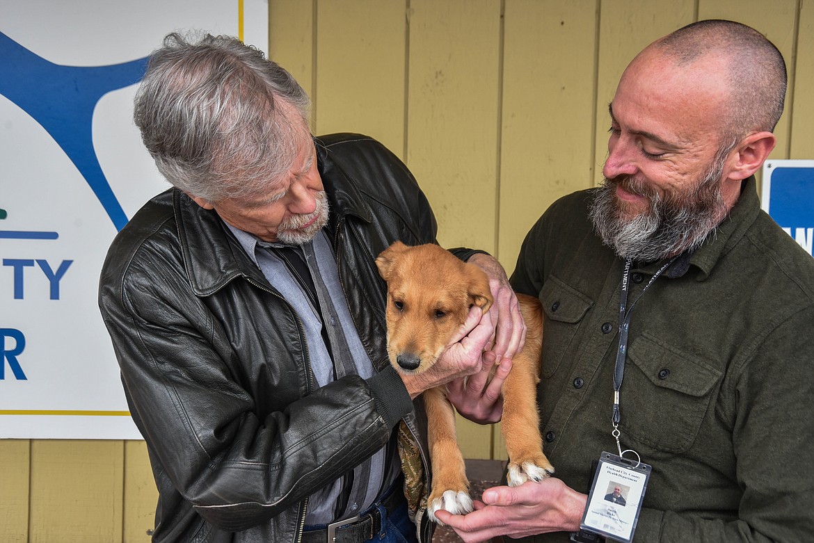 Colin Johnson, left, and Austin Hicks, right, hold a puppy named "The Grinch" at the Flathead County Animal Shelter on Dec. 14, 2023. Johnson recently donated $50,000 to the shelter. Hicks is the director of the shelter. (Kate Heston/Daily Inter Lake)