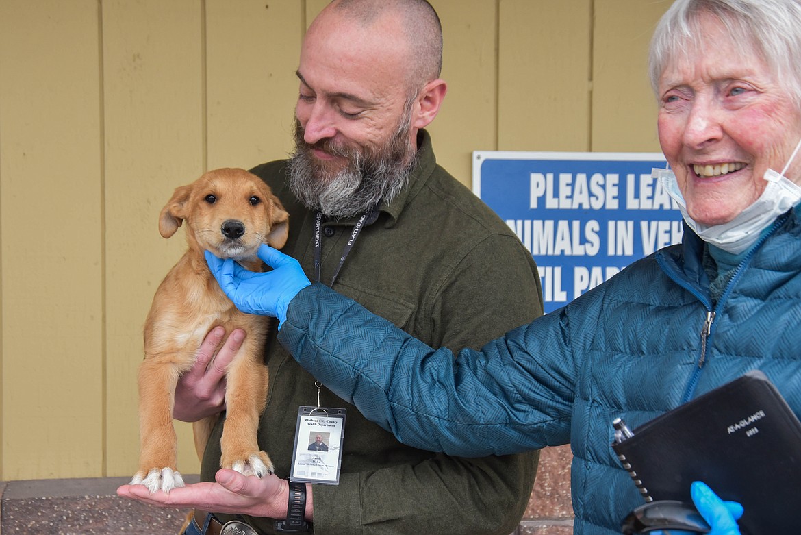 Austin Hicks, left, and Myni Ferguson, hold a puppy named "The Grinch" at the Flathead County Animal Shelter on Dec. 14, 2023. (Kate Heston/Daily Inter Lake)