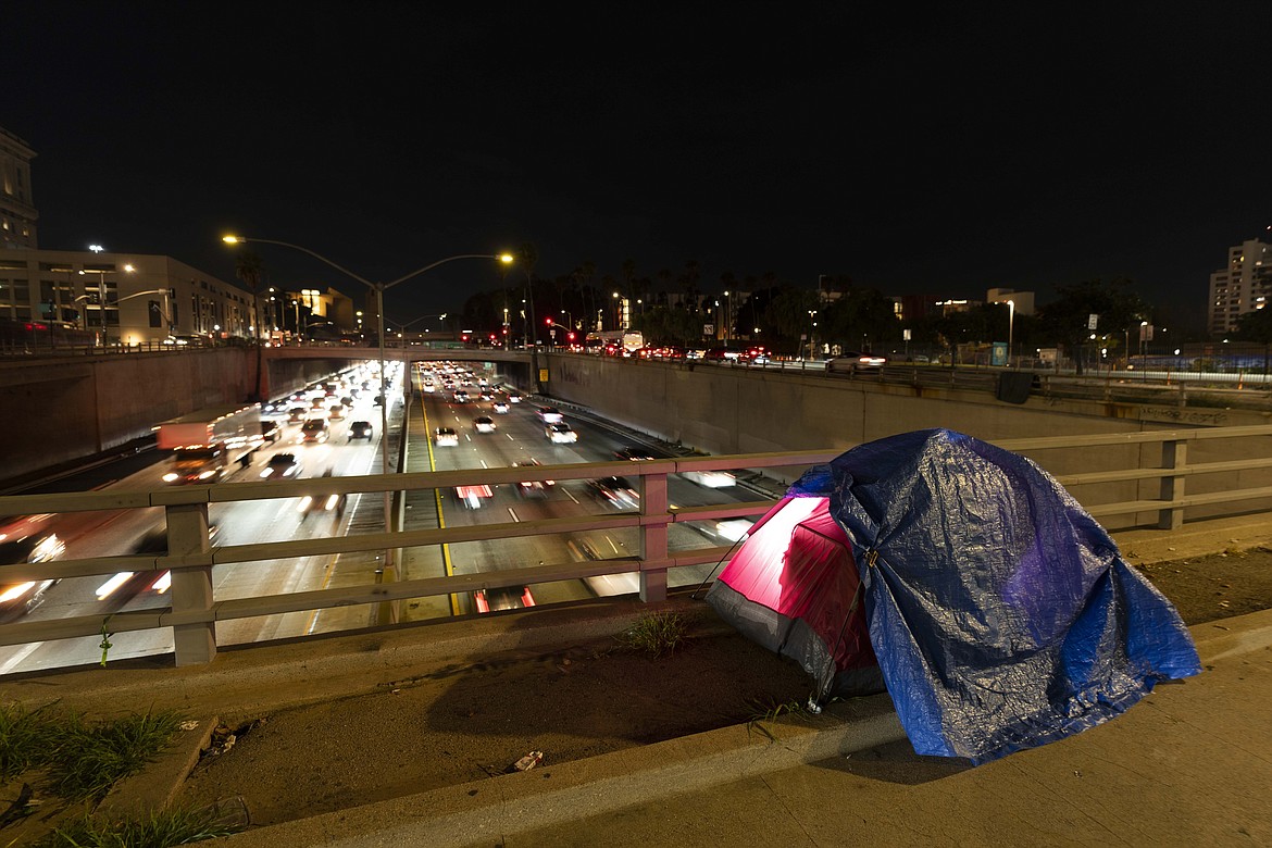 In this photo illuminated by an off-camera flash, a tarp covers a portion of a homeless person's tent on a bridge overlooking the 101 Freeway in Los Angeles, Thursday, Feb. 2, 2023. The United States experienced a dramatic 12% increase in homelessness as soaring rents and a decline in coronavirus pandemic assistance combined to put housing out of reach for more Americans, federal officials said Friday, Dec. 15, 2023. (AP Photo/Jae C. Hong, File)