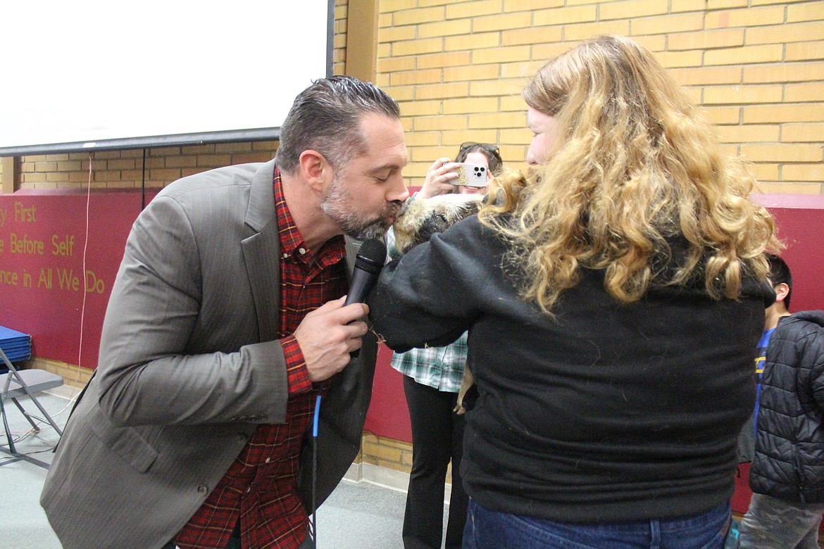 Midway Elementary School Principal Russell Kovalenko, left, gives a smooch to a pig as the payoff to students who donated more than 2,000 books to charity. Samantha Underwood holds the pig.