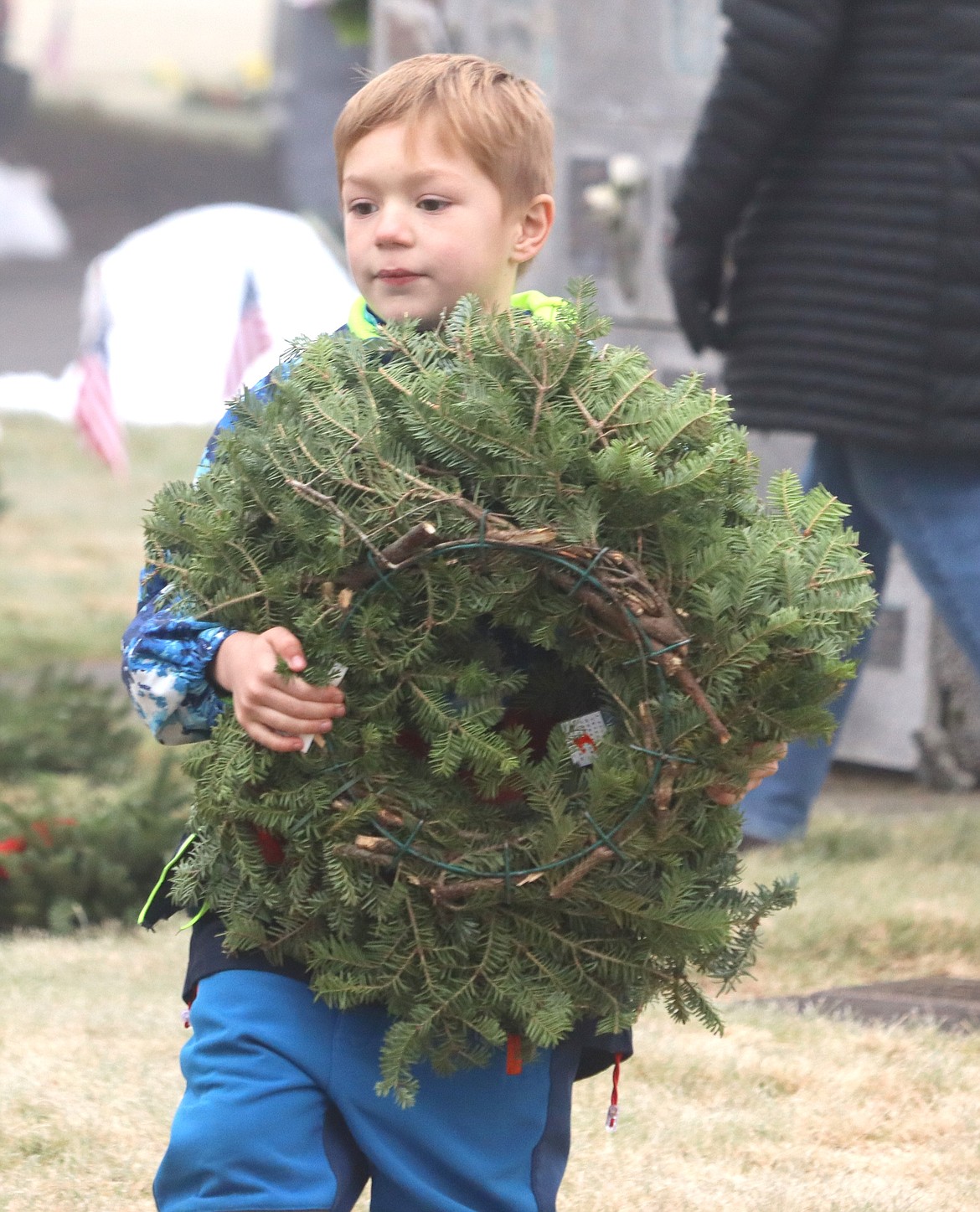 Morgen Budvarson carries a wreath at Coeur d'Alene Memorial Gardens on Saturday.