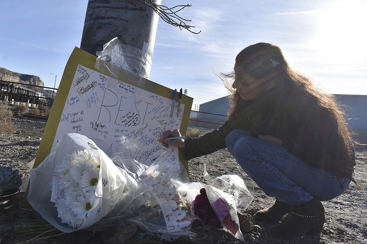 Jeannie Tuomala leaves a message on a sign, Sunday, Dec. 17, 2023, in Billings, Mont., at a memorial for four teenagers killed in a single-vehicle crash on Saturday, Dec. 16, in Billings. Police say speed, no seatbelts and possibly alcohol appear to have contributed to the accident. (AP Photo/Matthew Brown)