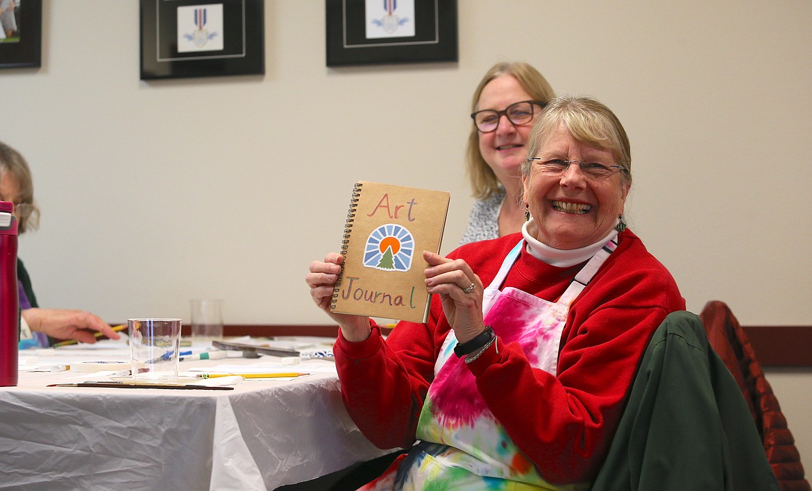 Vera Taggart, who spent 32 years of her 35-year teaching career in the Lakeland Joint School District, holds up her art journal Thursday as she and other members of the North Idaho Education Association Retired Chapter create illustrations that will be sold to support Idaho kids in need.