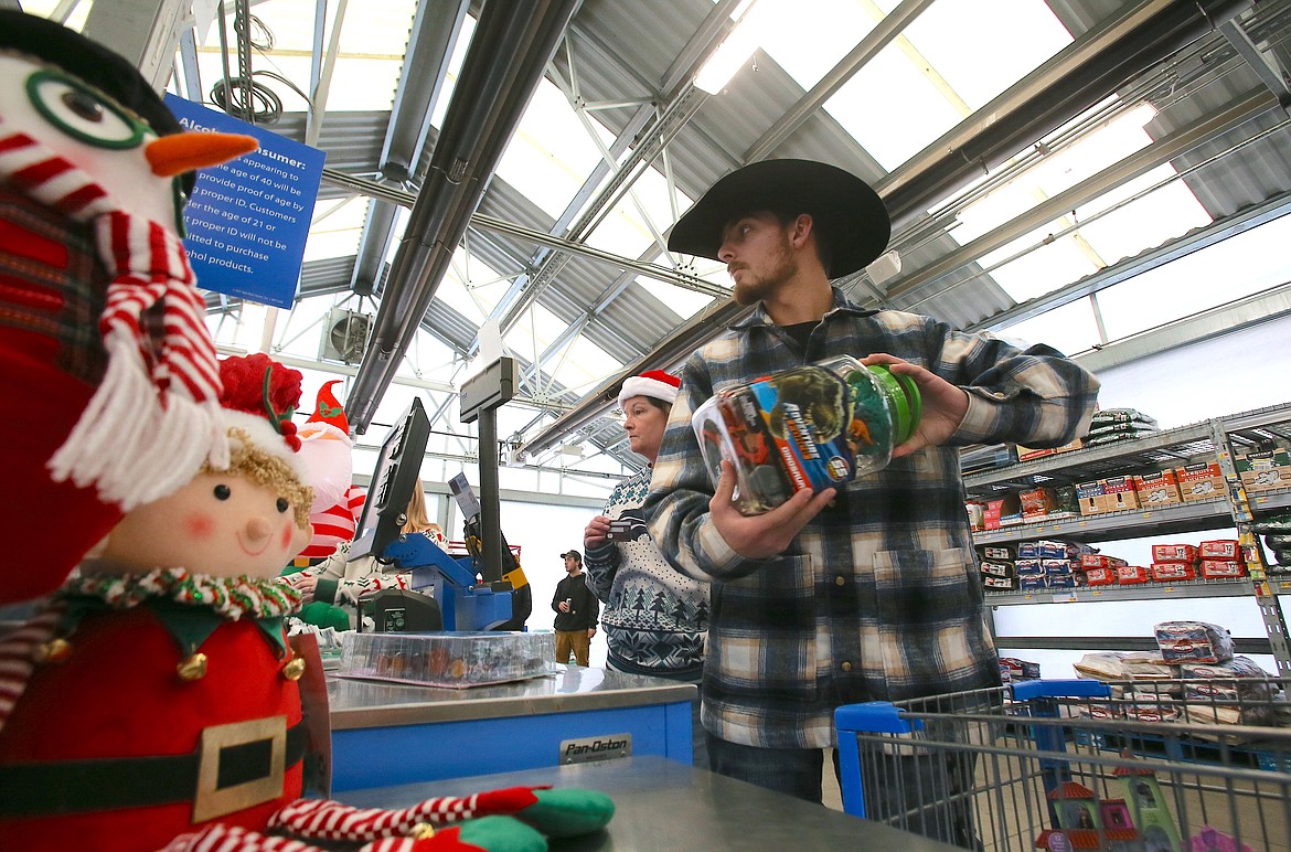Lake City High School senior and economics student Caden Dutra keeps an eye on his budget as items are scanned Tuesday morning at the Hayden Walmart. Dutra and his classmates raised about $10,300 to buy Christmas gifts and needed items for local families through the annual Give Back Project, which also serves as a real-world economics experience for the students.