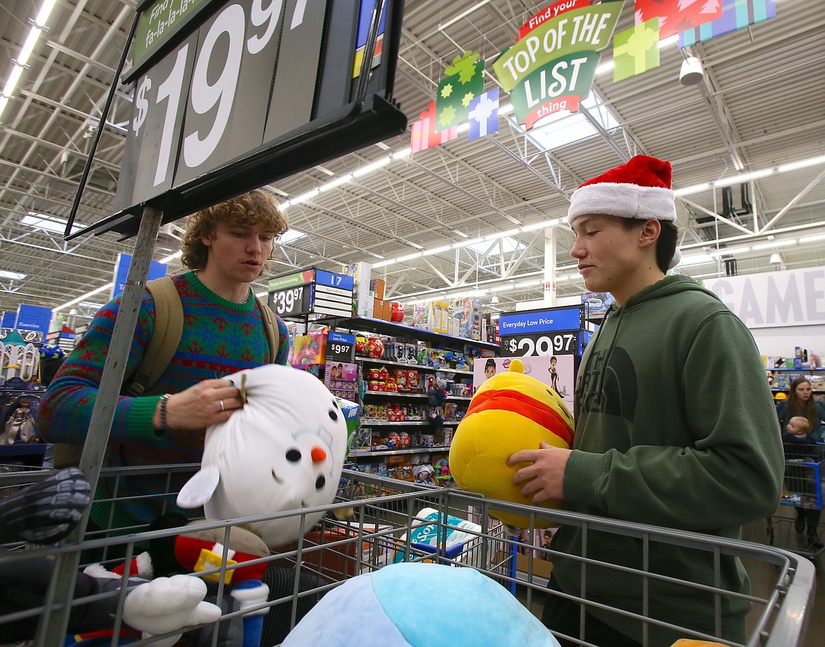 Seniors Micaiah Turcotte, left, and Connor Carmignani debate which squishy pillows to potentially purchase as Lake City High School economics students go Christmas shopping for local families Tuesday at Walmart for their annual Give Back Project.