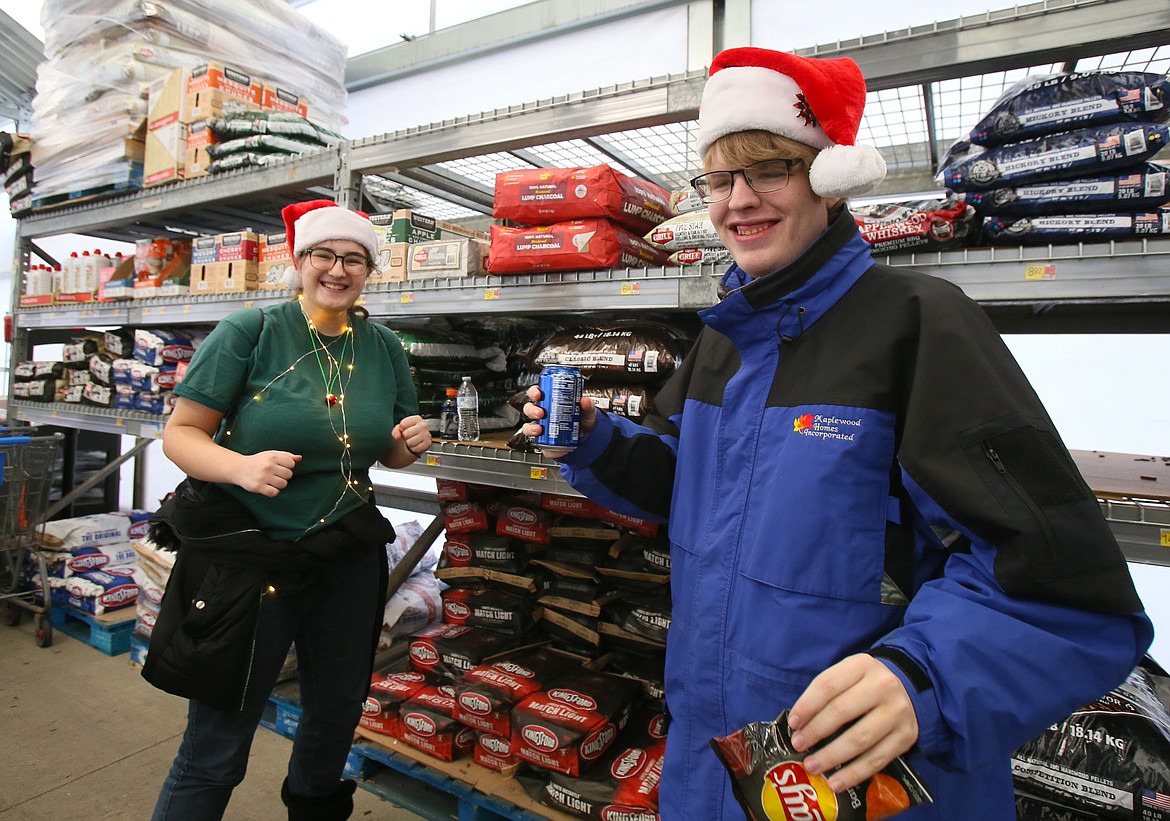 Seniors Kaydance Bean and Christopher McConnell are in the Christmas spirit Tuesday morning as they dance to holiday music while shopping for their Give Back Project families at the Hayden Walmart.