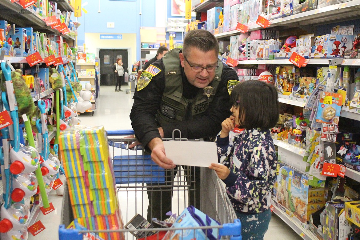 Adams County Sheriff Dale Wagner, left, and his shopping buddy Tereza cross names off the shopping list and consider the next step.