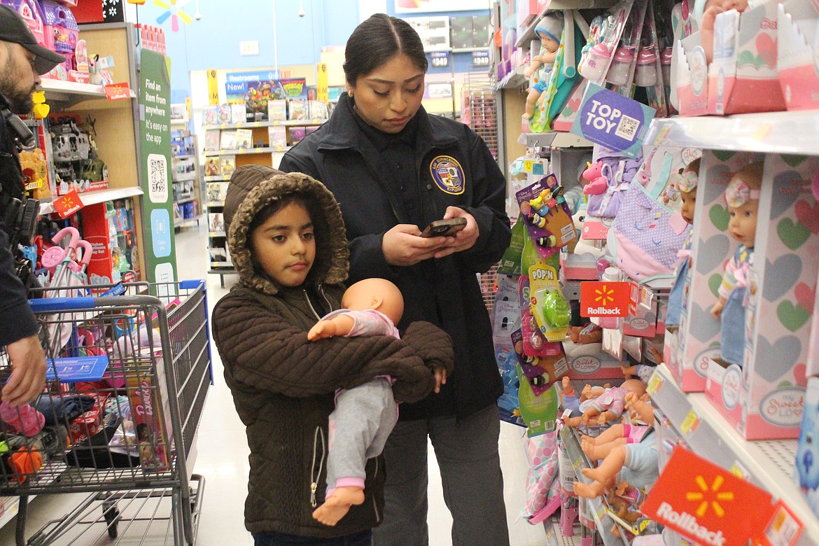 Rosa Sandoval, part of the Explorer program for the Othello Police Department, checks the budget while her shopping buddy Yomara thinks about a potential present.