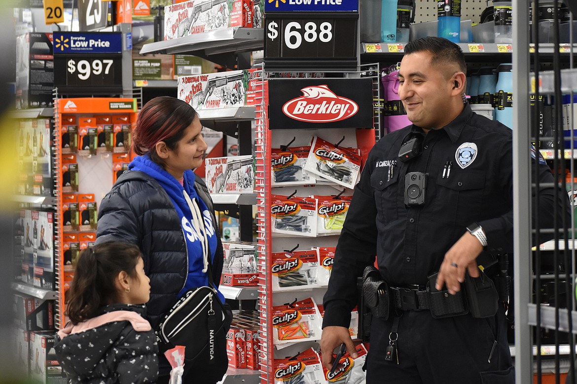 Ephrata Police Officer Marvin Canizales smiles as he speaks with a family during the Shop With a Cop event Monday night.