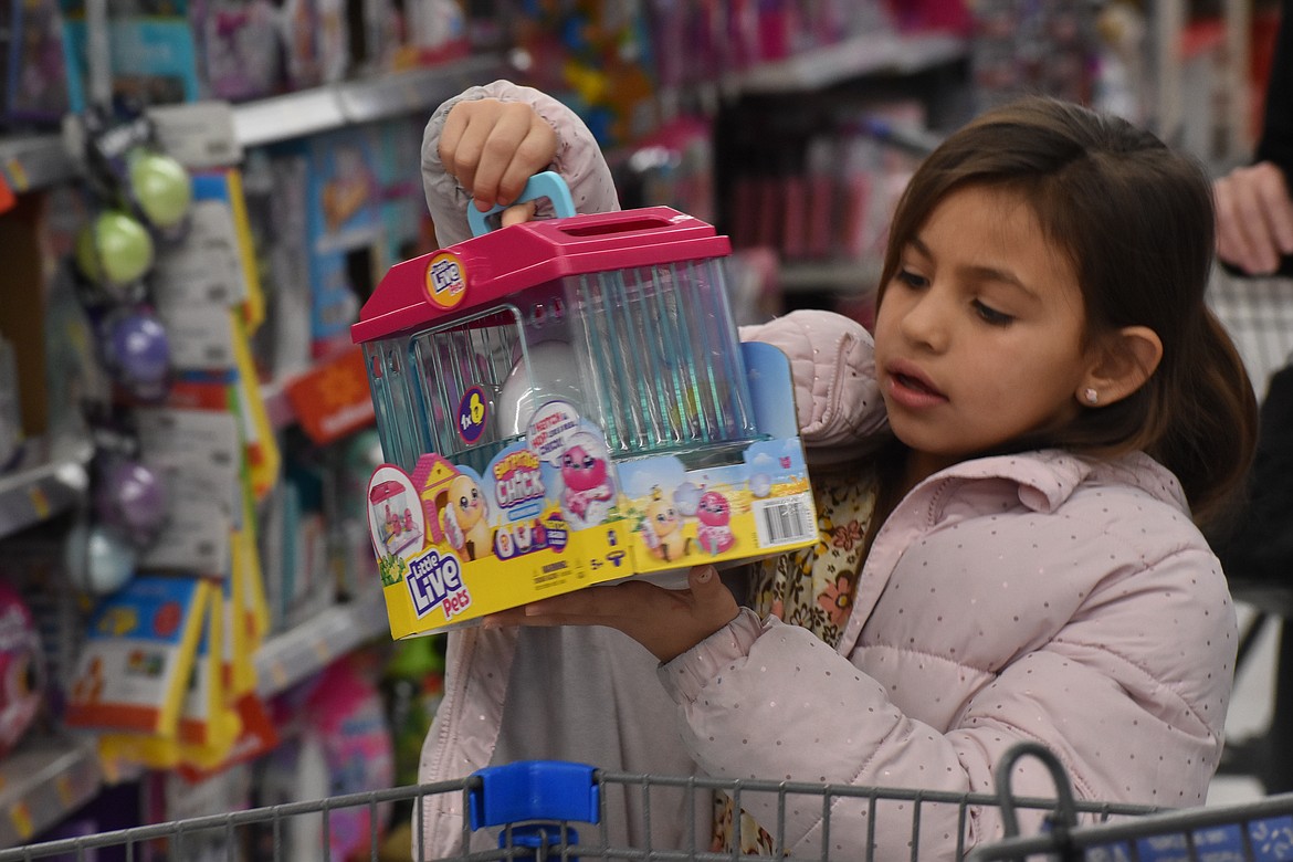 A girl picks out a toy to put in her shopping cart at the Shop With a Cop event Monday at the Ephrata Walmart.